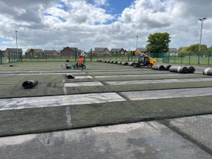 Workers using machinery to strip the artificial off of the football field.