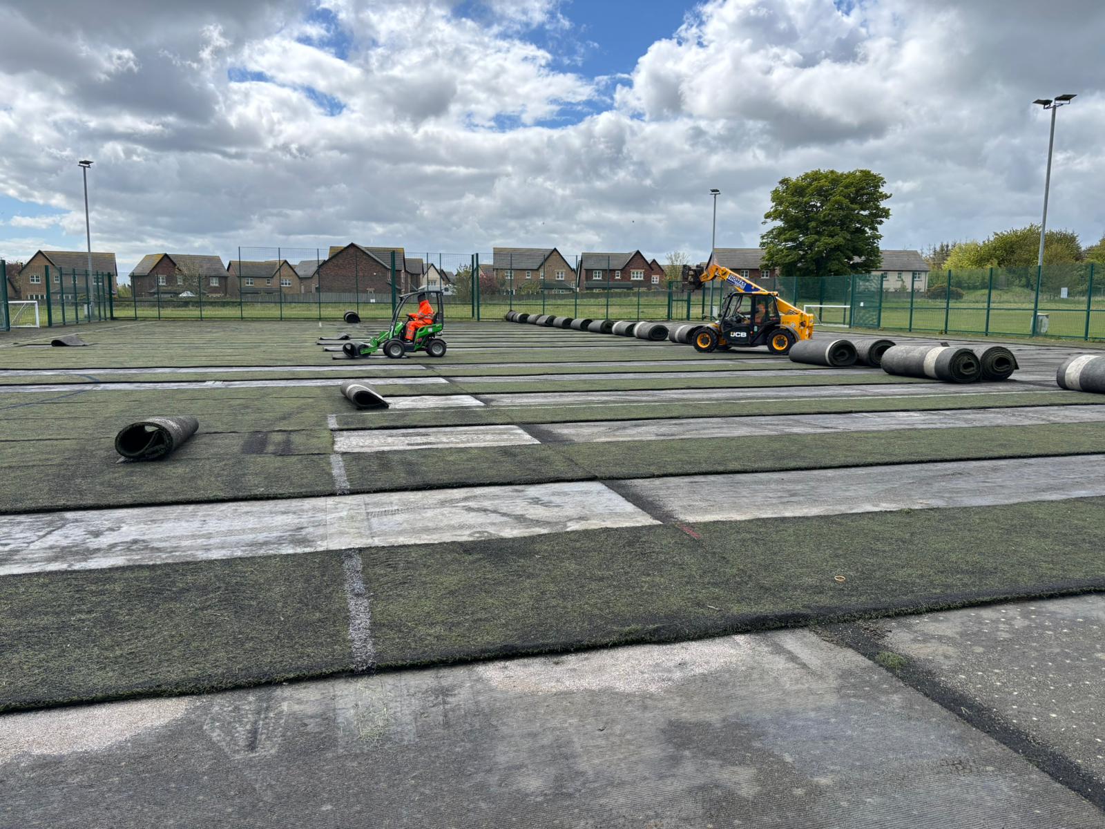 Workers using machinery to strip the artificial off of the football field.